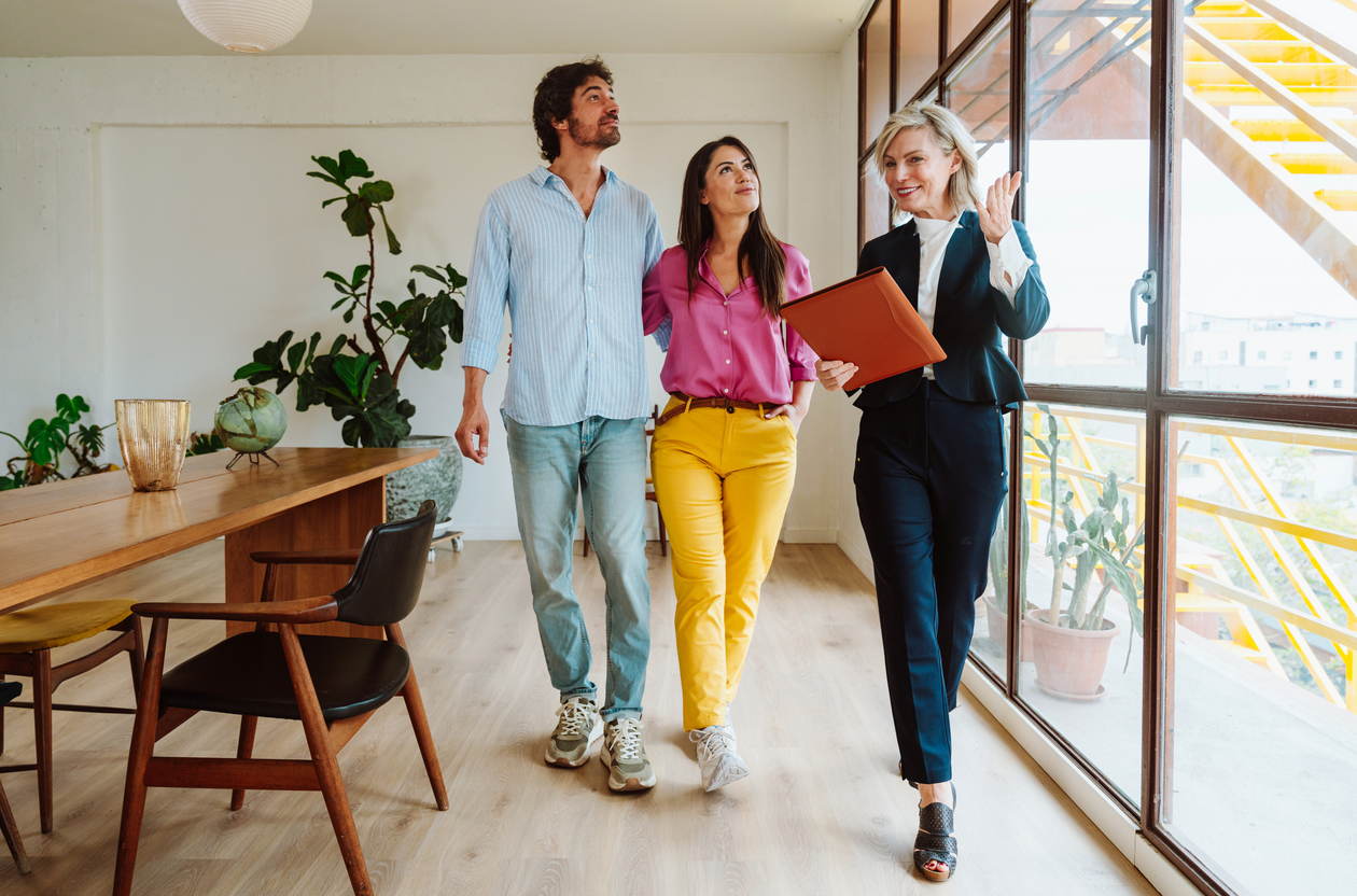 Real estate agent showing an apartment to a couple. Real estate agent showing document to smiling couple